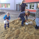 Sandspende für den Schulhof: Kinder beim Verteilen des Sandes
